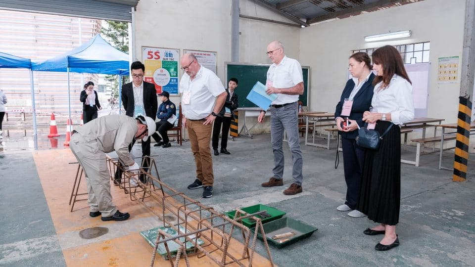 Praktische Prüfung in Hanoi: Ein Kandidat bearbeitet eine Bewehrung, die Prüfer aus Deutschland schauen zu